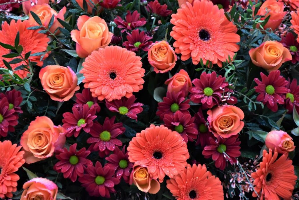 Eine Urne mit einem Kranz aus weißen Blumen auf einem Holztisch
