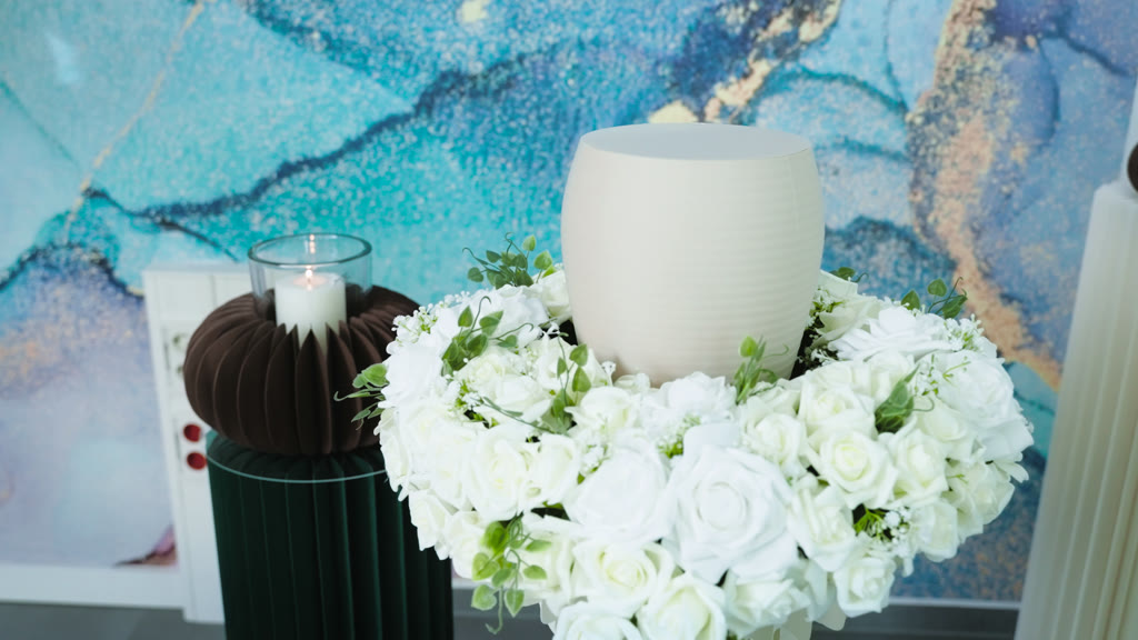 Helle Urne in einem Kranz aus weißen Rosen im Abschiedsraum
